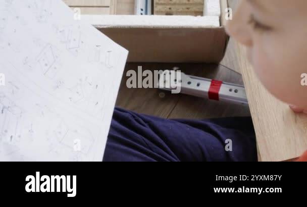 Young boy carefully studying assembly instructions while putting ...