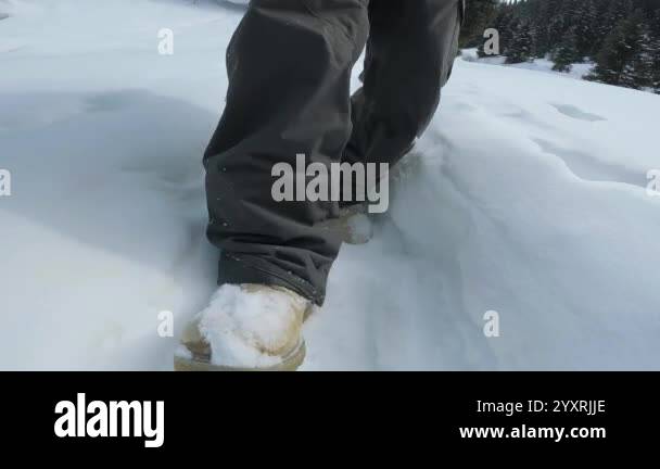 A snowy landscape featuring boots making tracks in deep snow, capturing ...