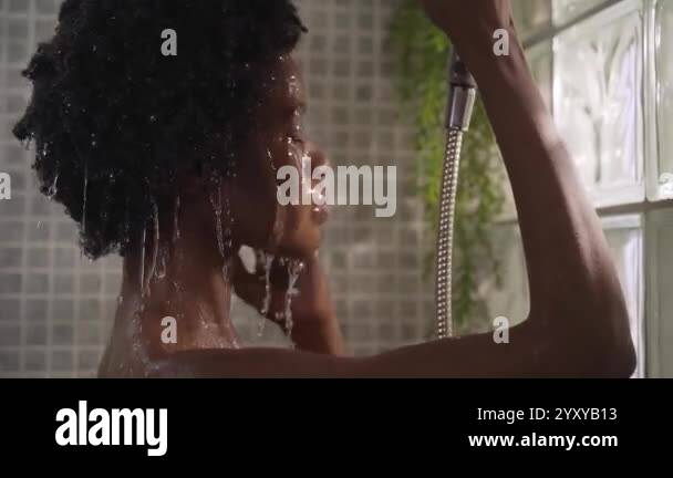 Adult afro black female gets hair and head wet with showerhead enjoying