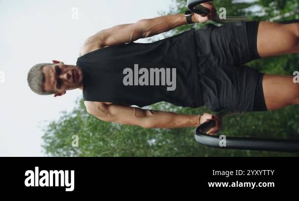 Athletic man has workout, hanging and pull up on parallel bars outdoors ...