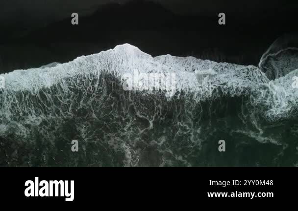 Foaming ocean waves roll onto shore creating white patterns aerial view ...