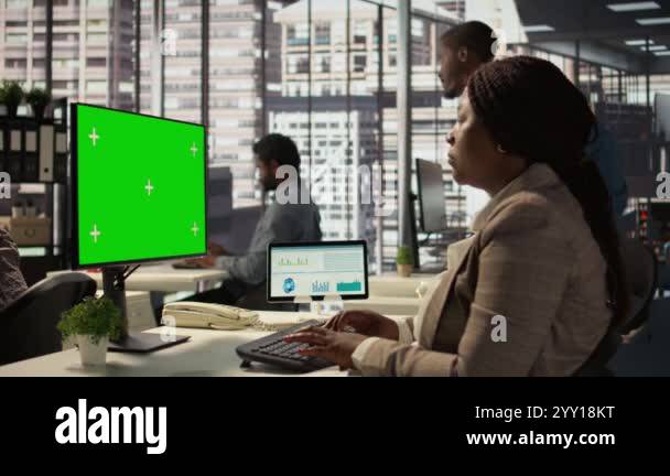 Female director seated at workstation with green screen on devices ...