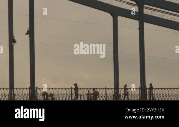 As the sun gradually sets on the horizon, people near the bridge