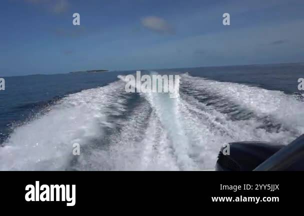 Waves from the engines of a high-speed boat. Rear view. Blue sky, white ...