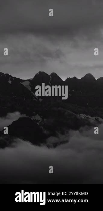A dramatic black and white scene of towering mountains surrounded by ...