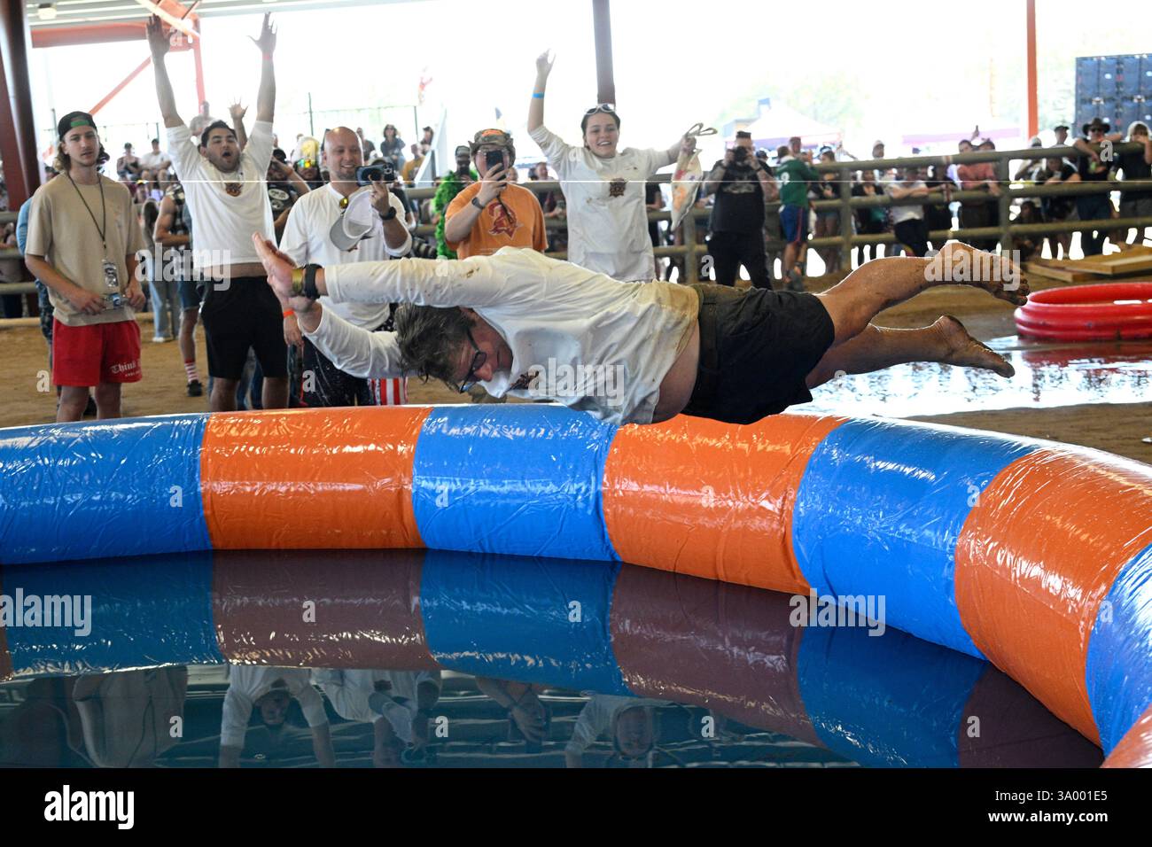 Tom Vars jumps into a pool of water after losing in the Human Beer Pong ...