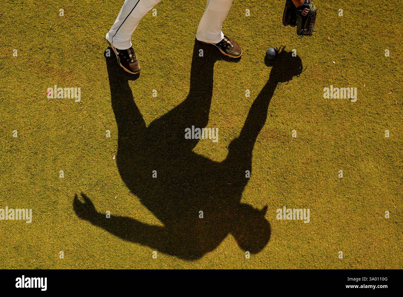 A Seattle Mariners pitcher casts a shadow while warming up in the ...