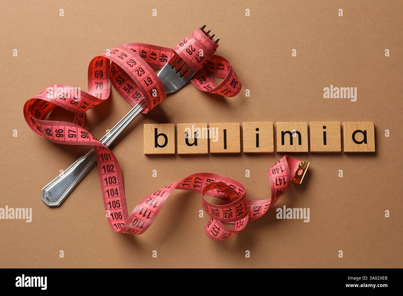 Word Bulimia, fork and measuring tape on brown background, top view Stock Photo