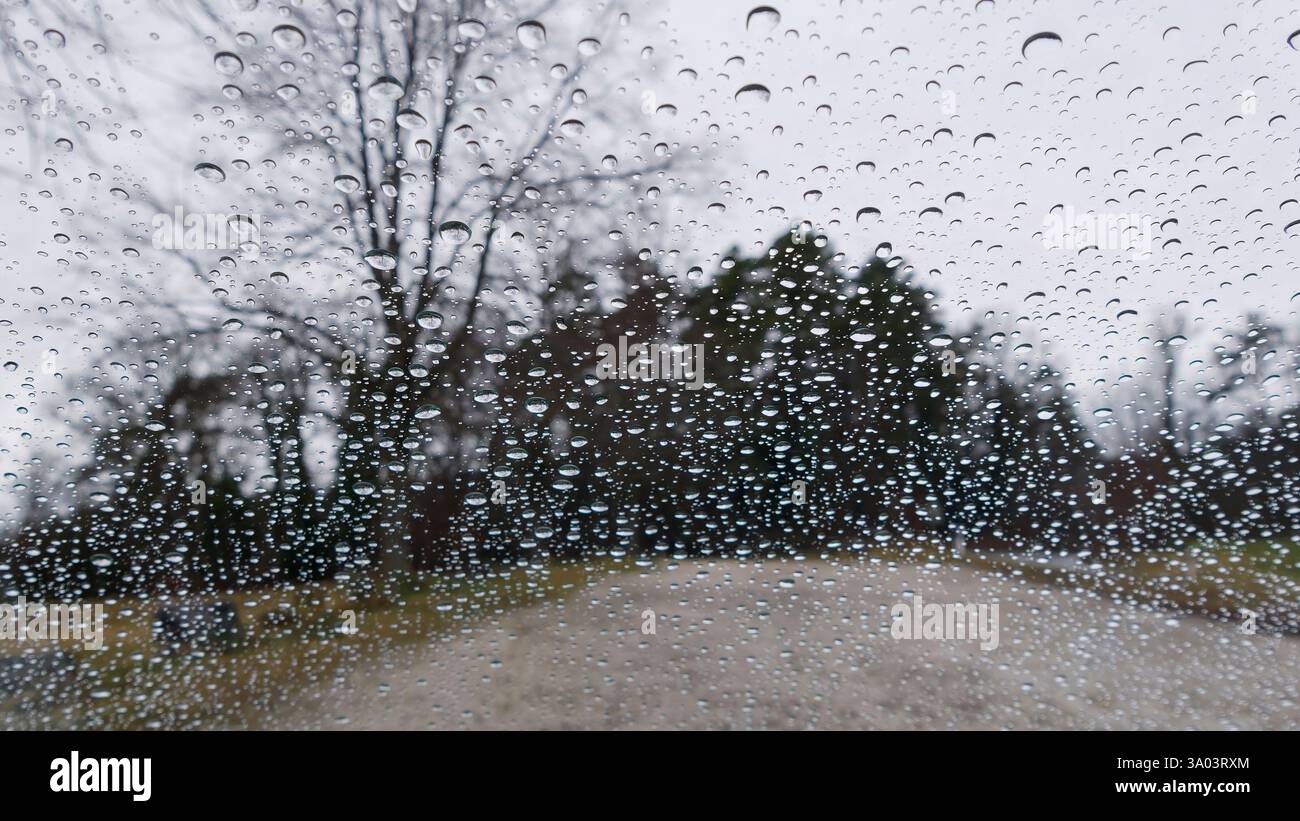 Raindrops on Glass with Blurred Outdoor Scenery in Background Stock Photo
