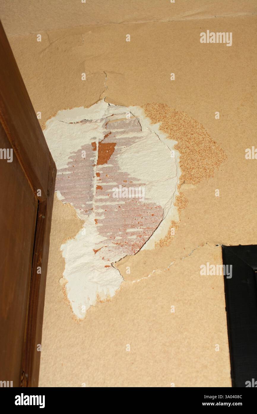 Wall damage reveals layers of paint and texture in an indoor space, highlighting maintenance needs and renovation opportunities Stock Photo