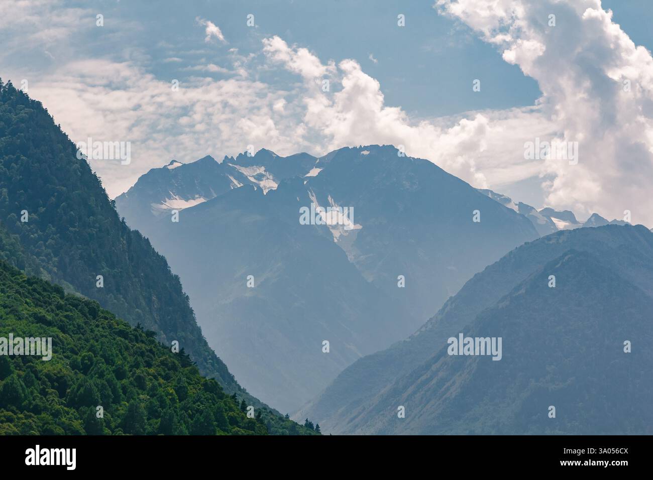Stunning view of snow capped mountain peaks rising above a lush green ...