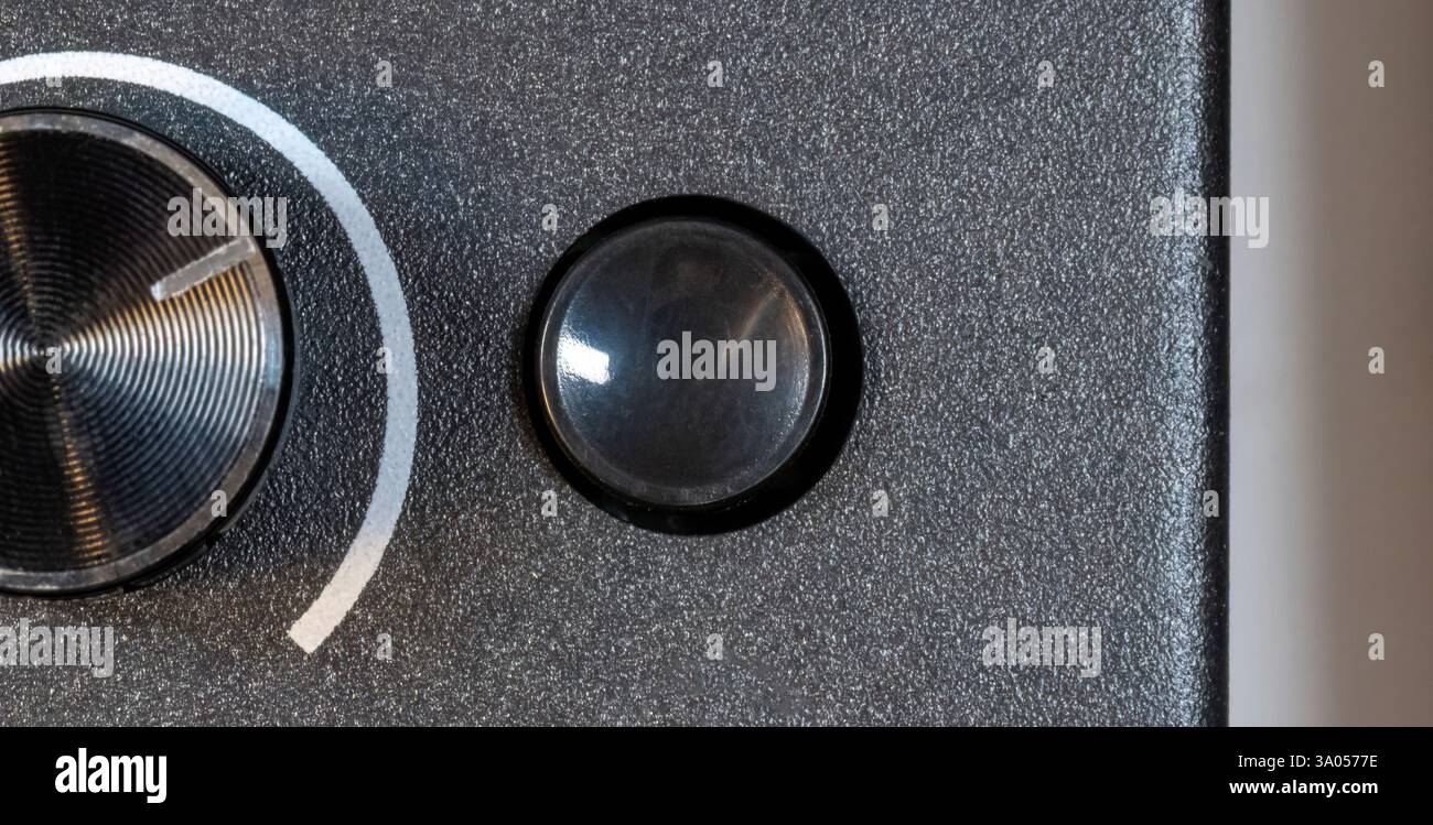 Above The Button Small round blank empty black button next to metallic knob on textured ...