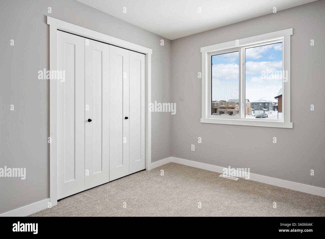White bedroom with a window and a closet. The room is very clean and empty. The window is open, letting in a cool breeze Stock Photo