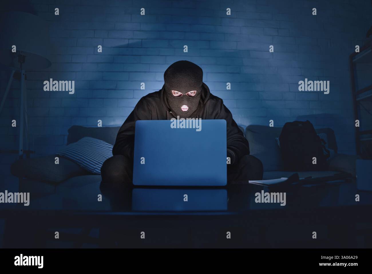 Masked hacker downloading private information using pc Stock Photo