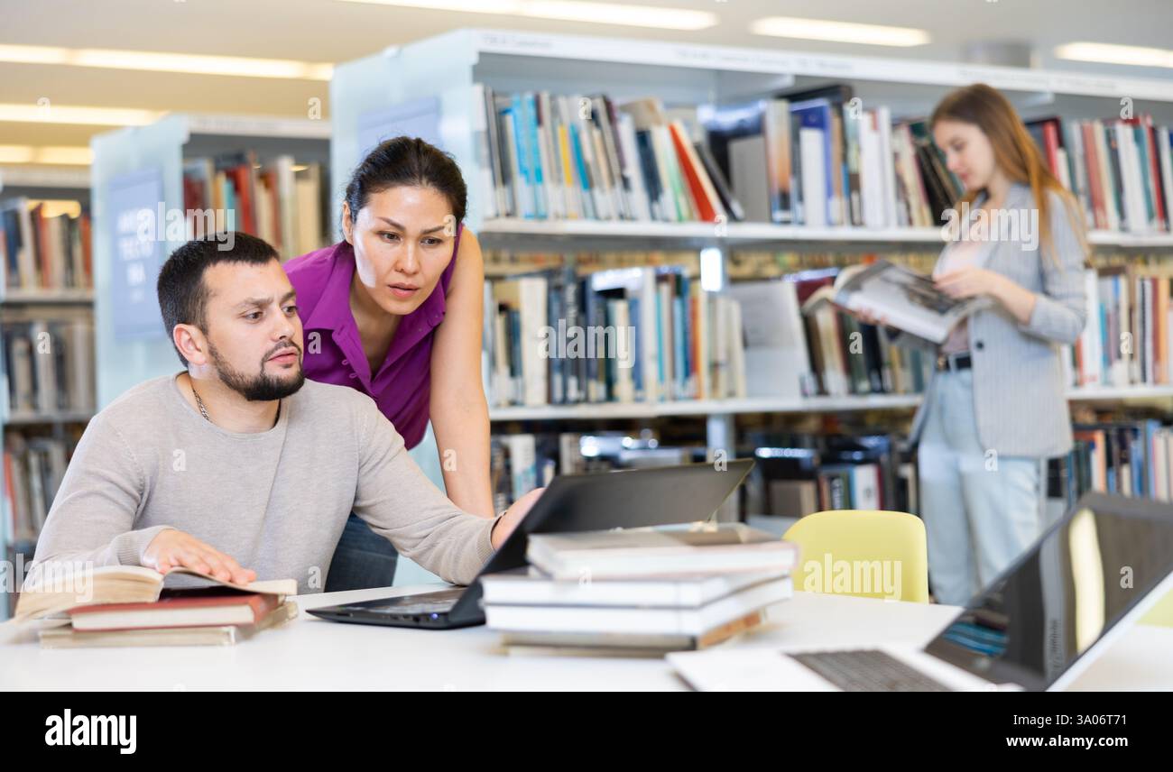 Two male and female students studying together in library Stock Photo