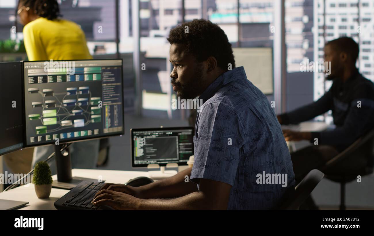 Computer scientist resuming work after strolling in workspace, doing software debugging using PC. Man walking with tablet in office, fixing coding issues using computer, camera A Stock Photo