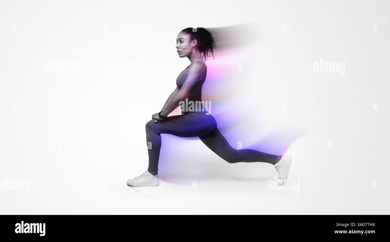 African American woman in activewear performing forward lunges on pink backdrop Stock Photo