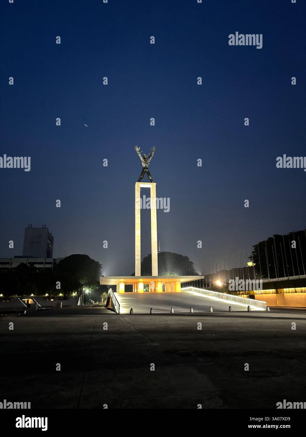 A stunning early morning view of the West Papua Liberation Monument, Jakarta. illuminated by soft golden lights against the deep blue sky. - Smartphone Captured Stock Image