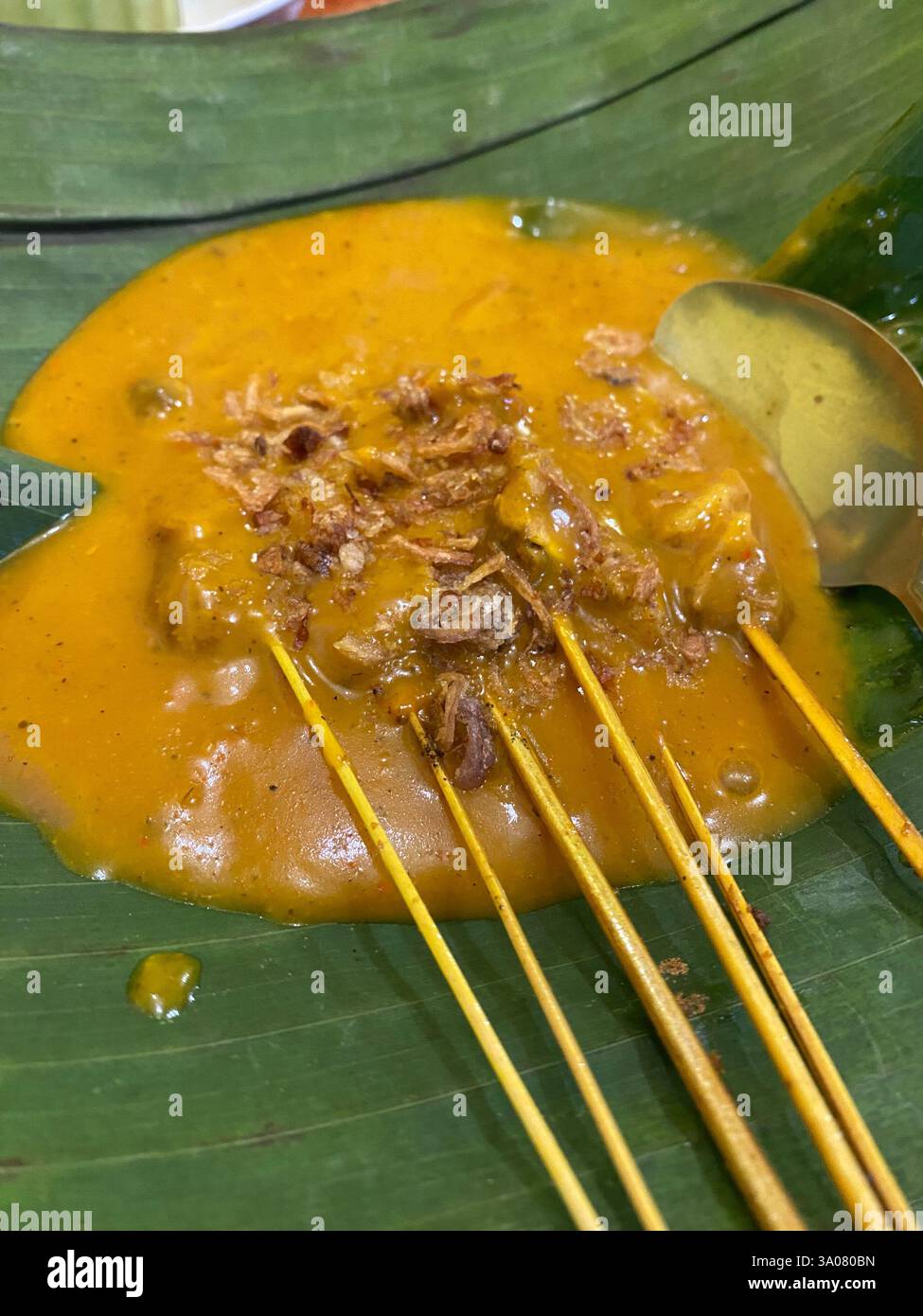 Authentic Indonesian Padang satay served with thick, spiced curry sauce on a banana leaf. A delicious street food specialty - Smartphone Captured Stock Image