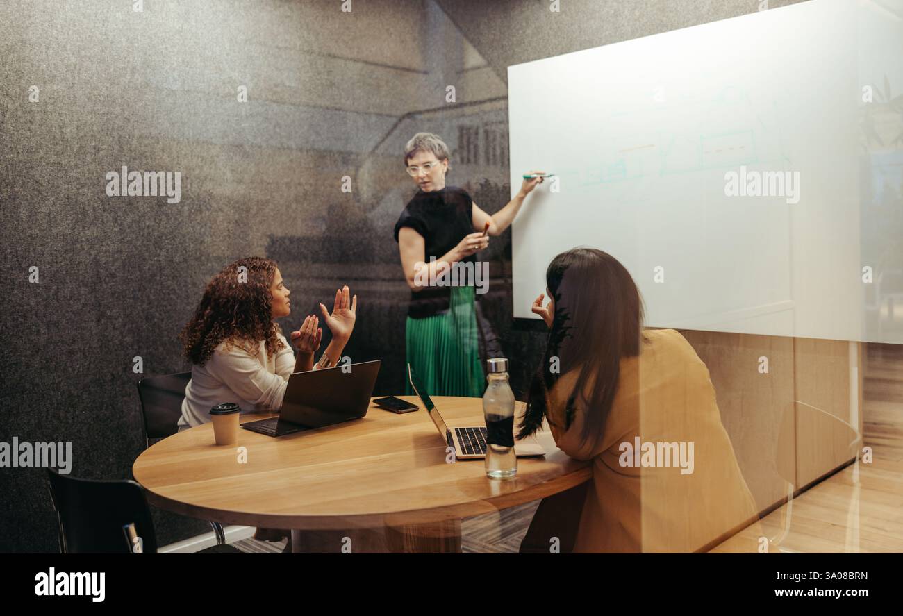 Three women engage in a collaborative brainstorming session within a ...
