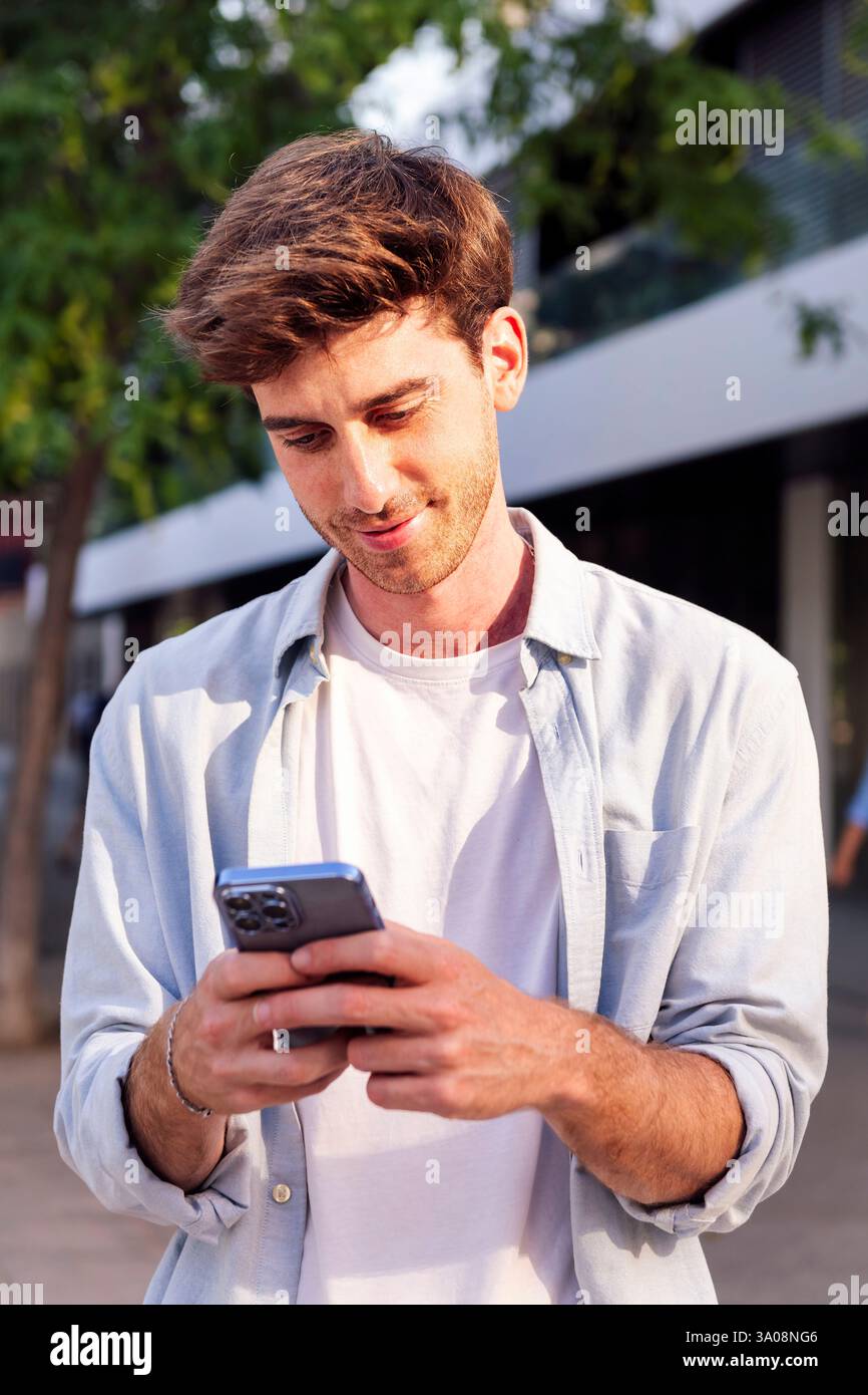 man using cell phone while walking down the street Stock Photo