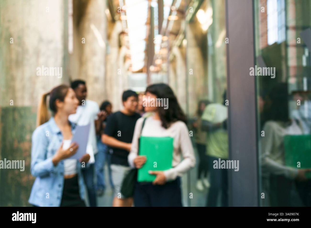 Defocused students talking while walking in corridor at university Stock Photo
