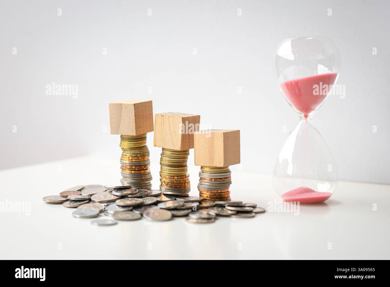 3 blank wooden square blocks on top of coins, next to sand timer ...