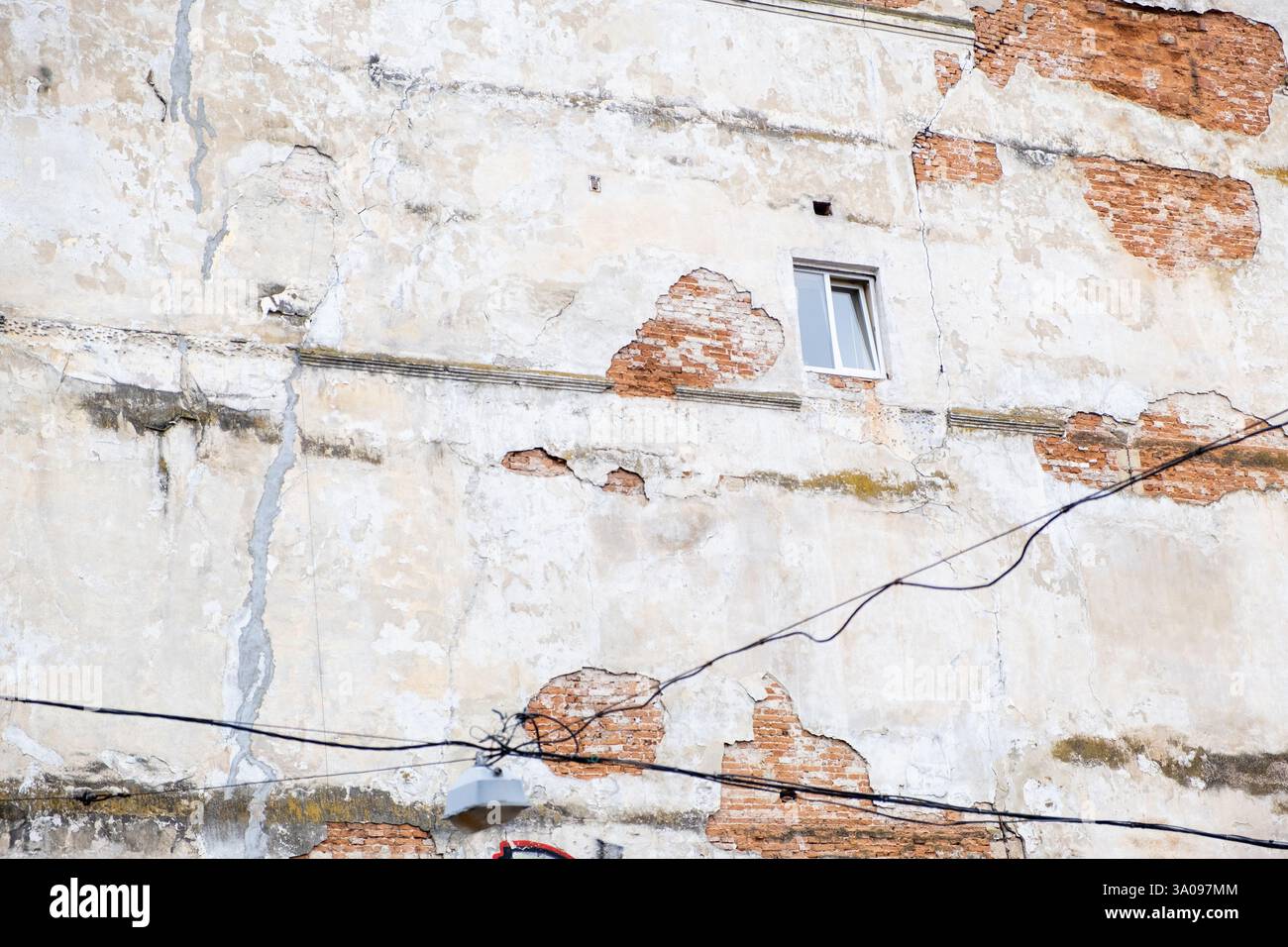 Weathered Building Facade with Exposed Bricks and Window Stock Photo