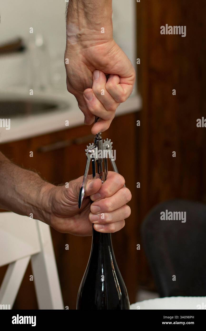Close up man opening a wine bottle with corkscrew Stock Photo