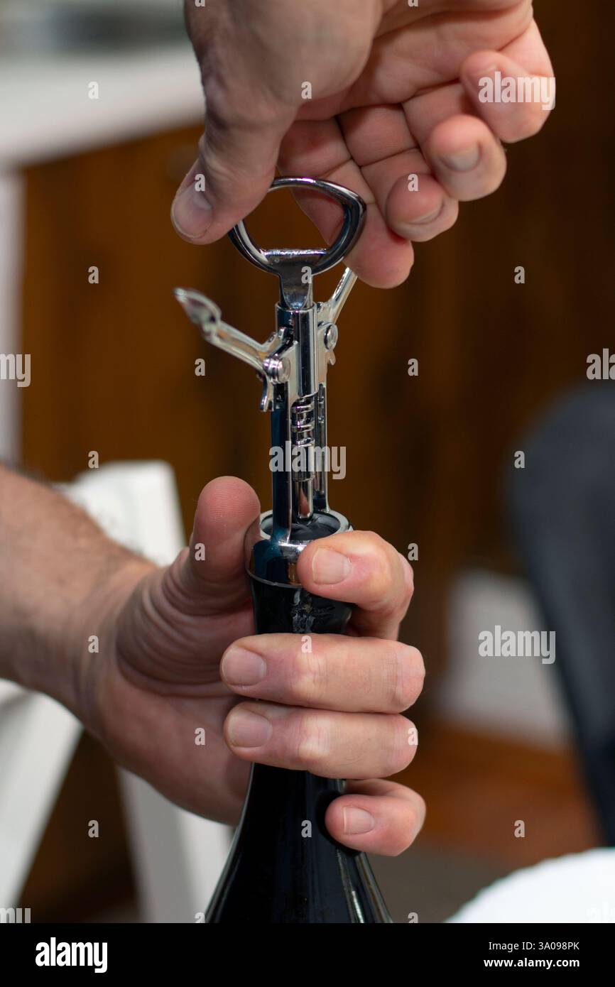 Opening a red wine bottle with stainless steel corkscrew closeup Stock Photo