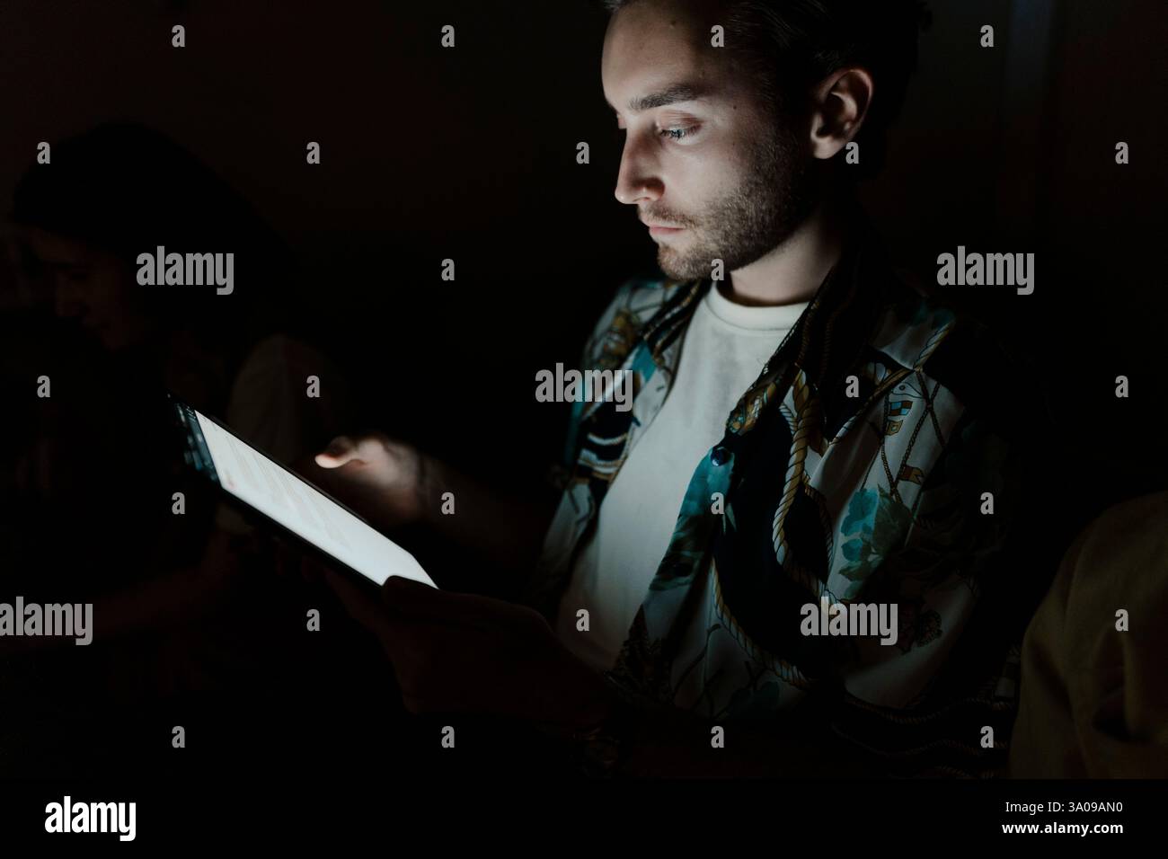 Male entrepreneur using tablet PC in darkroom Stock Photo