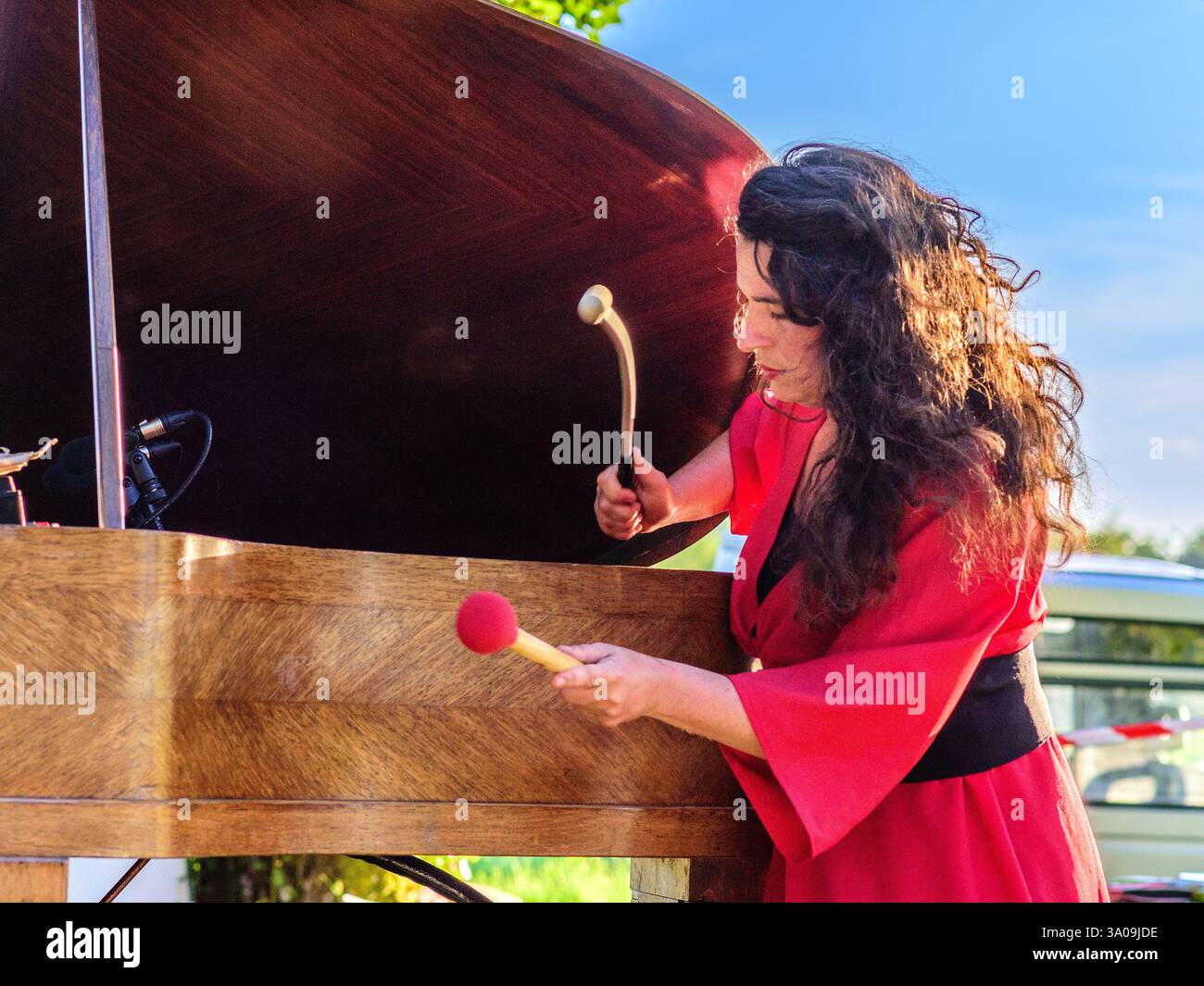 Violette Prévost as "La Pianiste Rouge" with her mobile grand piano performing at open-air concert - Indre (36), France. Stock Photo