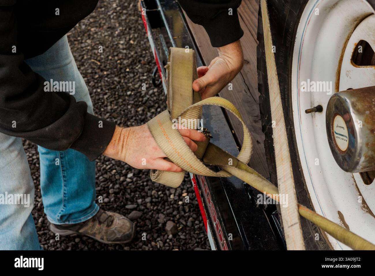 Close-up of hands securing a ratchet strap on a trailer wheel Stock ...