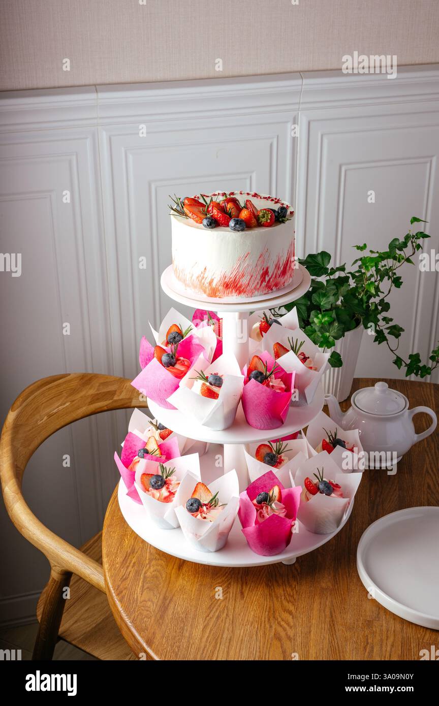 cupcakes and cake with berries on a stand Stock Photo