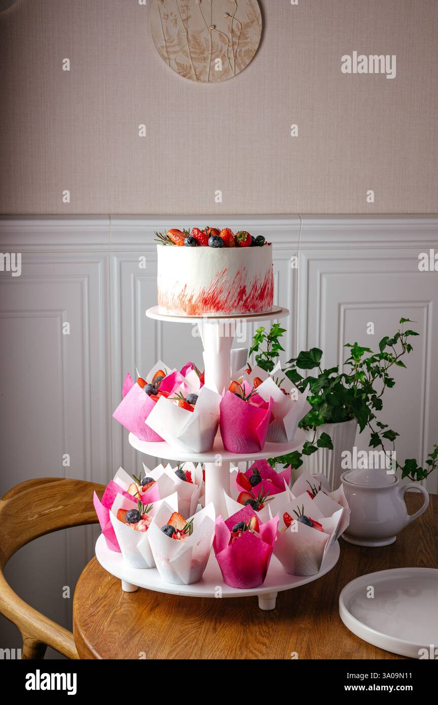 cupcakes and cake with berries on a stand Stock Photo