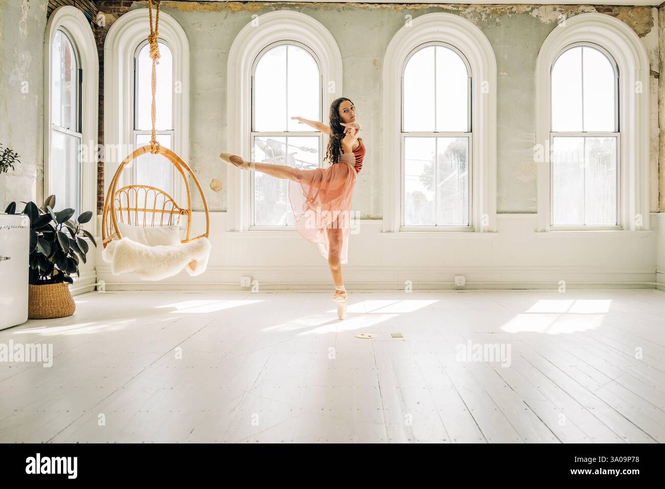 Ballerina performs an arabesque in a sunlit studio Stock Photo