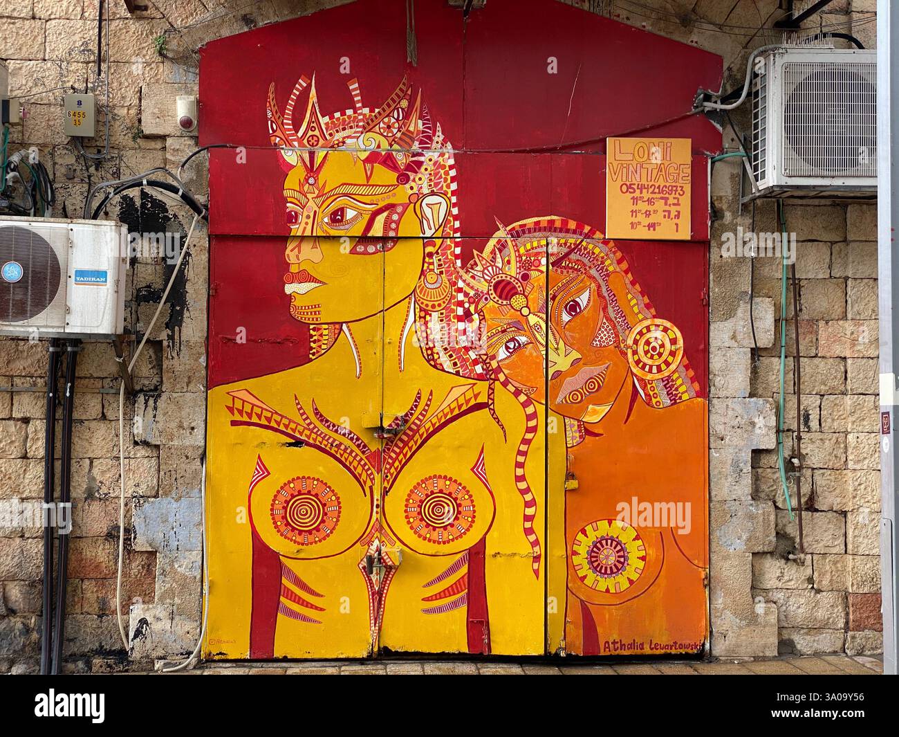 'Vibrant street art in Tel Aviv, Israel, depicting two abstract, tribal-inspired female figures on a rustic stone wall. This bold and expressive mural - Smartphone Captured Stock Image