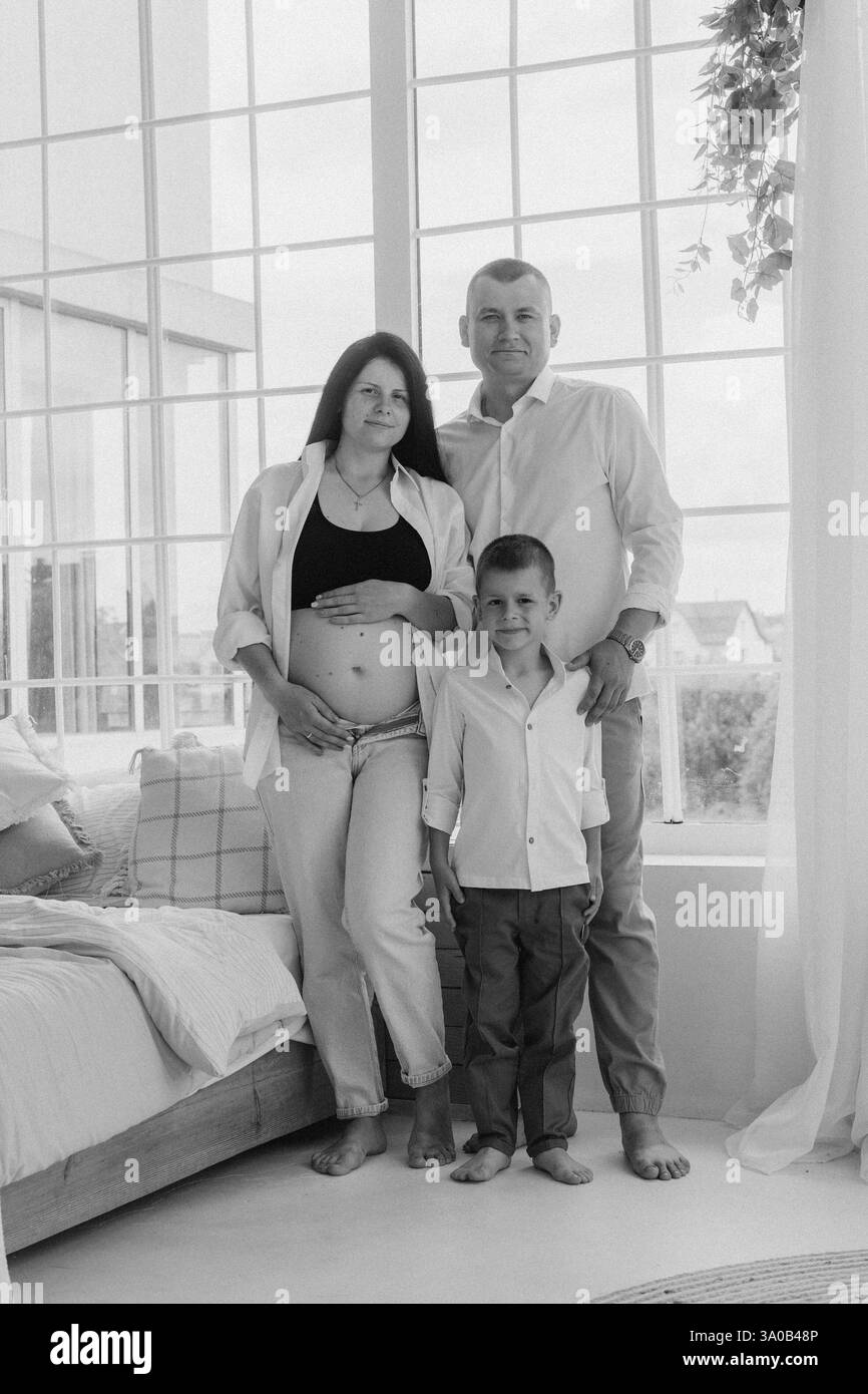 Family pregnancy photoshoot with father, pregnant mother, and son Stock Photo
