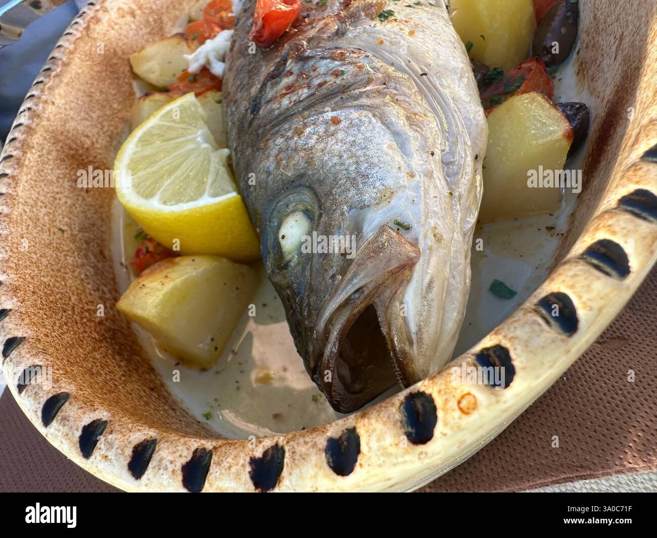Fresh catch of the day! ?? Oven-baked whole fish with potatoes, olives, and lemon—Mediterranean flavors at their best! ??️ #SeafoodLover - Smartphone Captured Stock Image