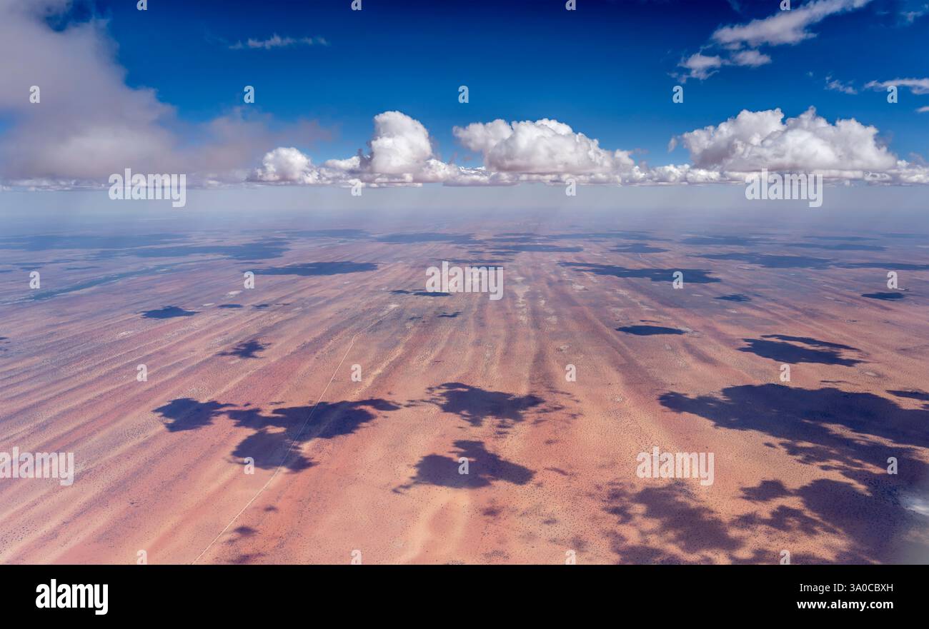 aerial landscape with bright clouds casting shadows over stripes of red ...