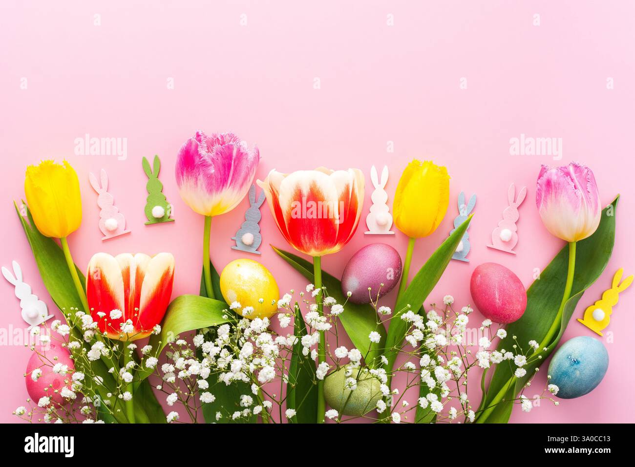 Spring Easter background, multi-colored Easter eggs and tulips with gypsophila on a pink background, copy space Stock Photo