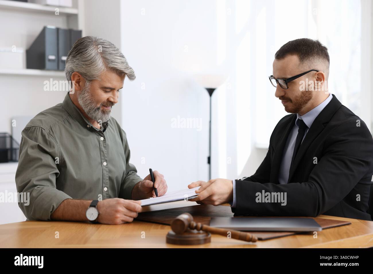 Client signing notarial paperwork during meeting with lawyer at wooden ...