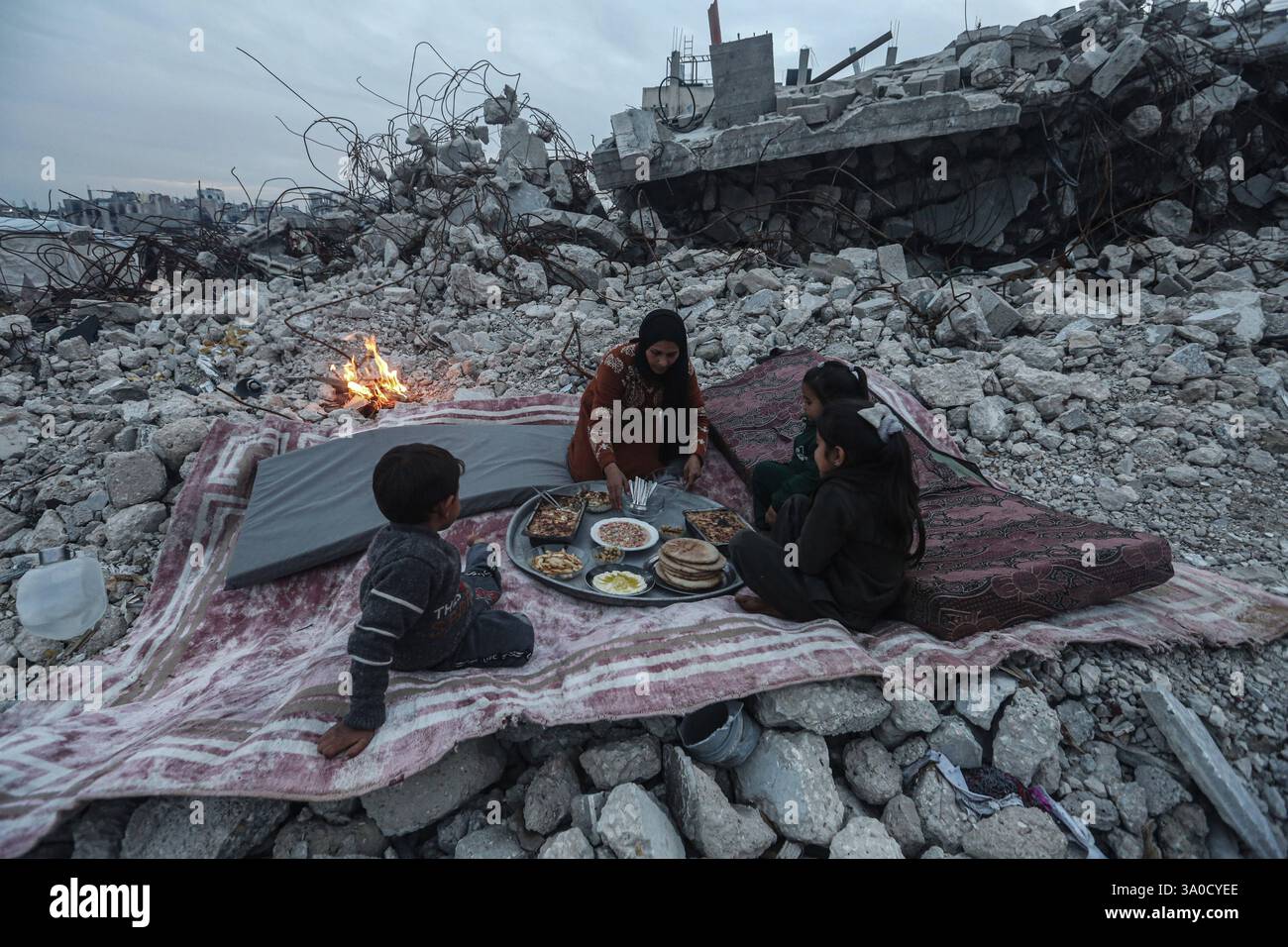 Palestinian Karam Abu Haloub and his wife Faten prepare iftar food during the third day of the holy month of Ramadan Palestinian Karam Abu Haloub and his wife Faten prepare iftar food during the third day of the holy month of Ramadan in a tent they set up on the ruins of their destroyed home in the Al-Shimaa area of Beit Lahia in the northern Gaza Strip, 03 March 2025. Thousands of Palestinian families in the Gaza Strip live in tents amidst a lack of basic necessities after the Israeli war on the Gaza Strip. Photo by Omar Ashtawy apaimages Beit Lahia Gaza Strip Palestinian Territory 030325 Bit Stock Photo