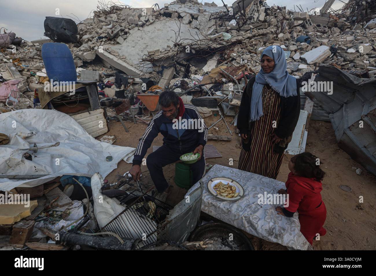 Palestinian Karam Abu Haloub and his wife Faten prepare iftar food during the third day of the holy month of Ramadan Palestinian Karam Abu Haloub and his wife Faten prepare iftar food during the third day of the holy month of Ramadan in a tent they set up on the ruins of their destroyed home in the Al-Shimaa area of Beit Lahia in the northern Gaza Strip, 03 March 2025. Thousands of Palestinian families in the Gaza Strip live in tents amidst a lack of basic necessities after the Israeli war on the Gaza Strip. Photo by Omar Ashtawy apaimages Beit Lahia Gaza Strip Palestinian Territory 030325 Bit Stock Photo