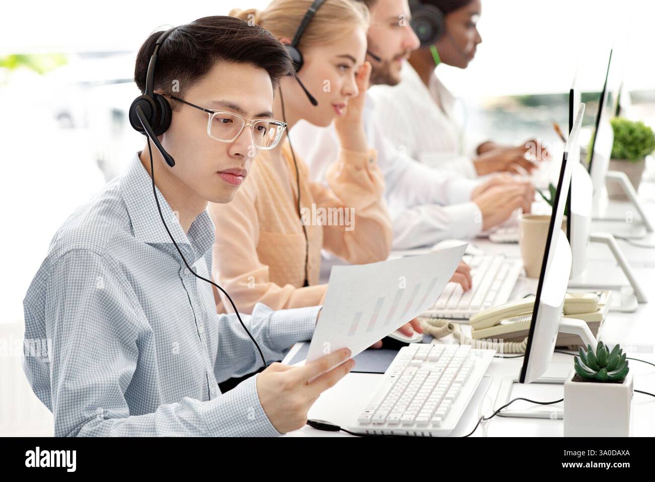 Asian hotline operator working with documents, providing technical support services to clients, free space Stock Photo