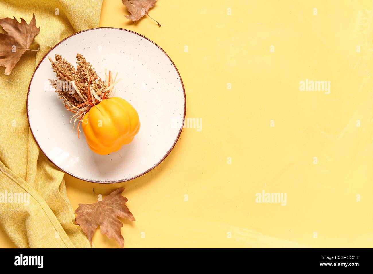Stylish autumn table setting with dry maple leaves on yellow background Stock Photo
