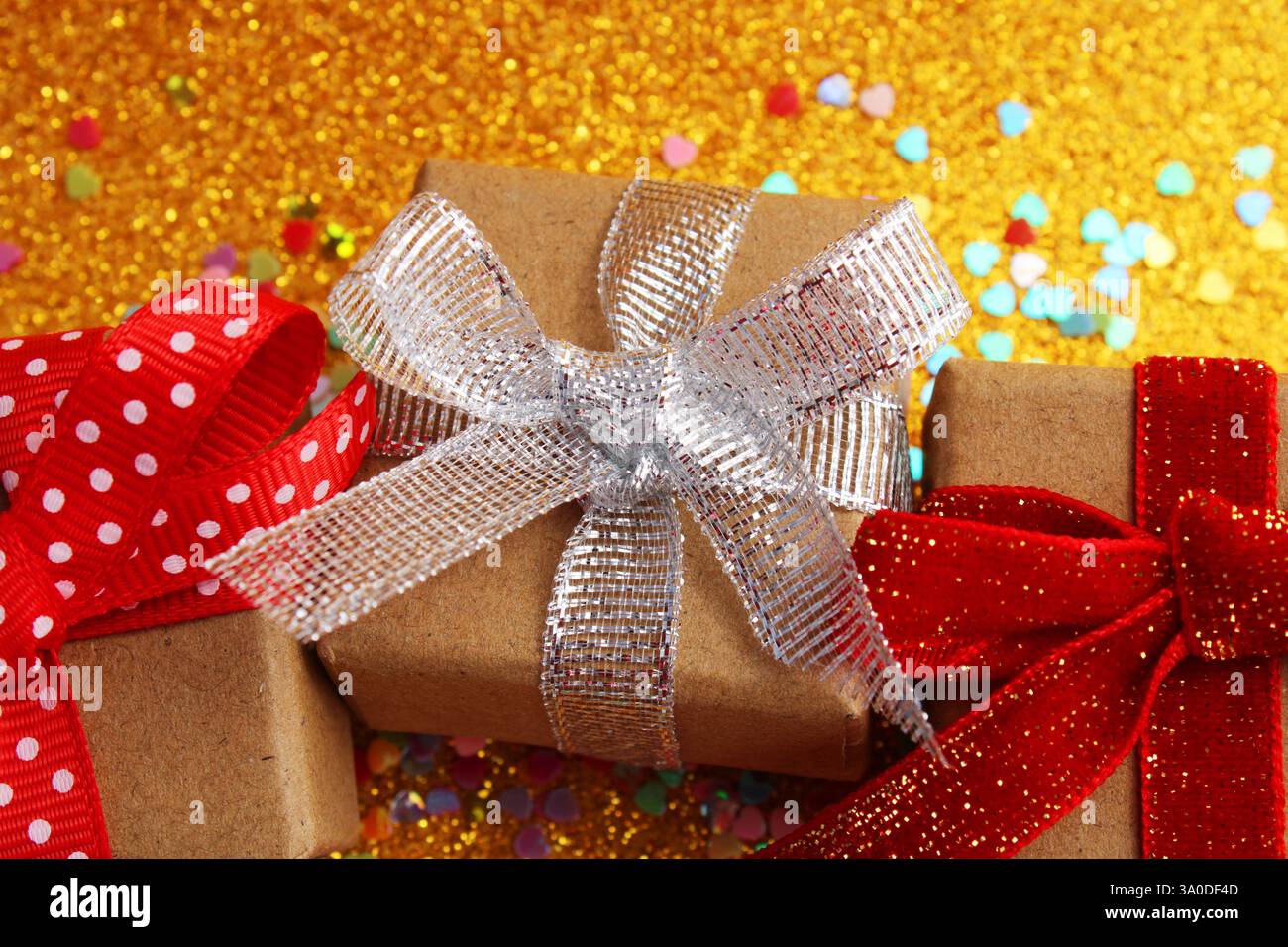 Three gift boxes with different bows next to colorful hearts Stock Photo