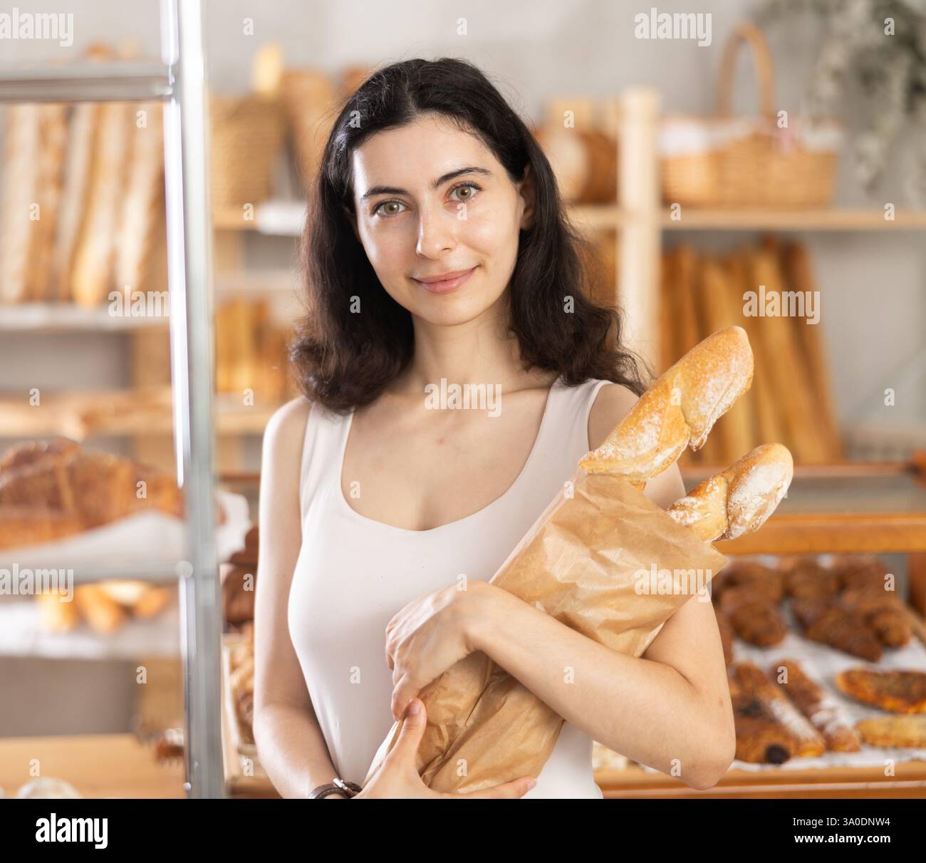 Young woman buying baguettes in bakery