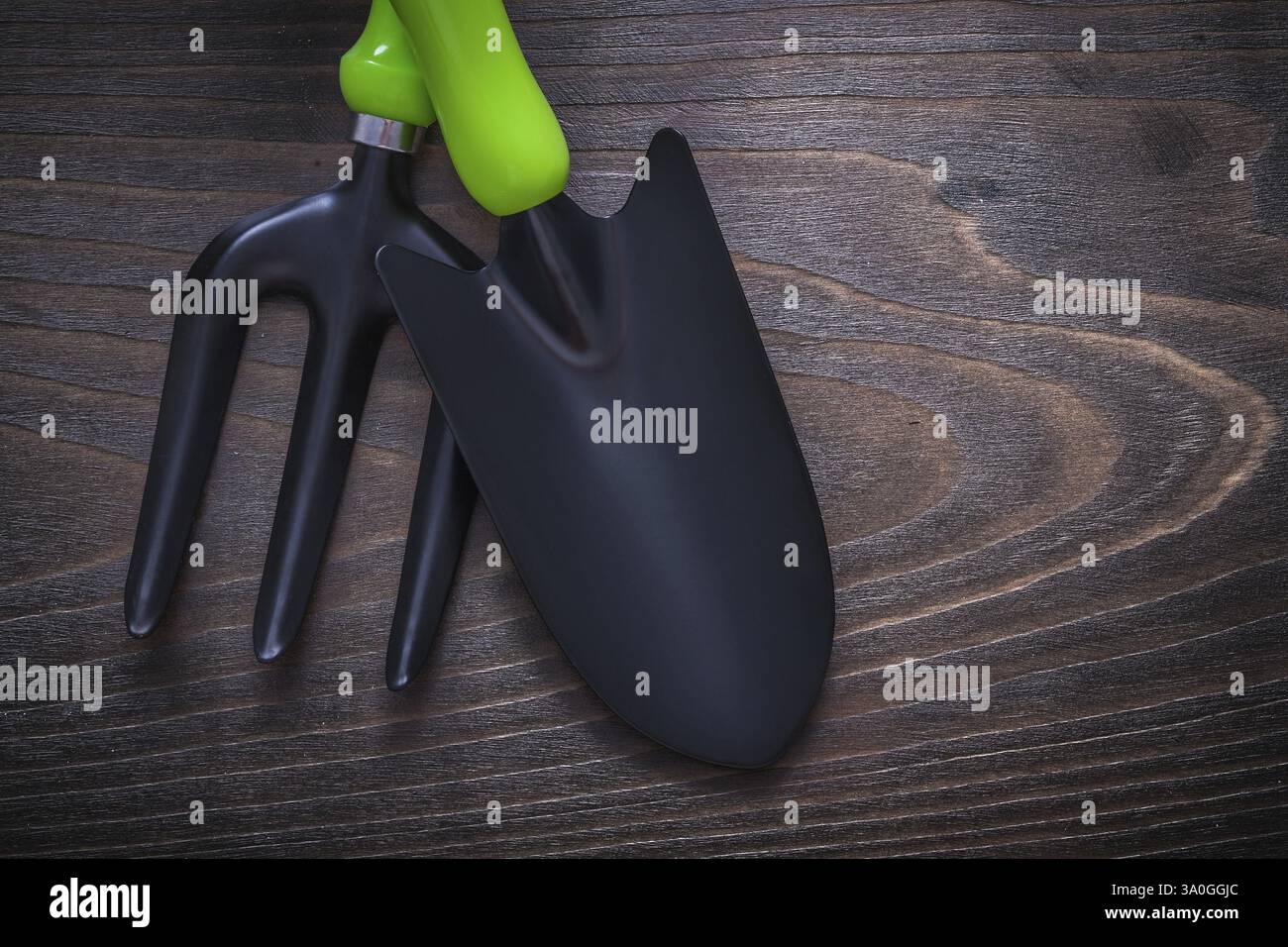 Black hand spade and trowel fork on vintage wooden board gardening concept Stock Photo