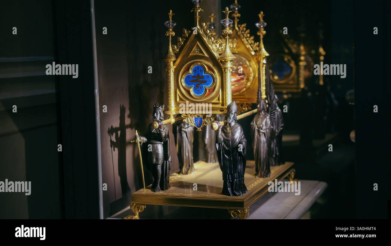 Ornate religious artifact rests under soft light in Chambery, highlighting detailed figures and craftsmanship from history. Stock Photo
